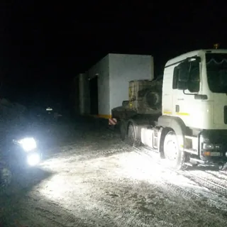 Грузовой автомобиль ИТТ с промышленным грузом ночью на заснеженной площадке