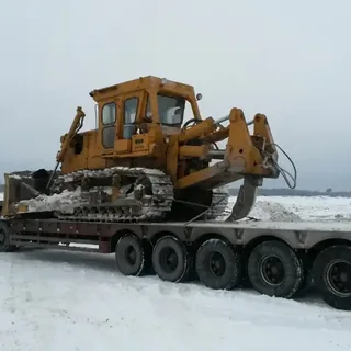 Перевозка гусеничного бульдозера на низкорамном трале по зимней дороге
