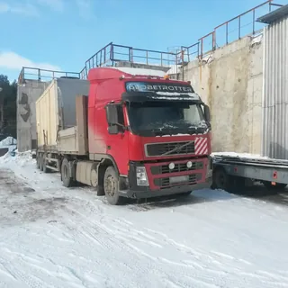 Грузовой автомобиль ИТТ перевозит крупногабаритный груз на промышленной площадке зимой