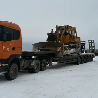 Перевозка бульдозера Komatsu на низкорамном трале по заснеженной площадке