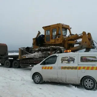 Перевозка бульдозера на трале с автомобилем сопровождения зимой