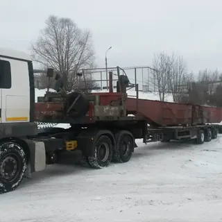Грузовой тягач с низкорамным тралом на заснеженной площадке